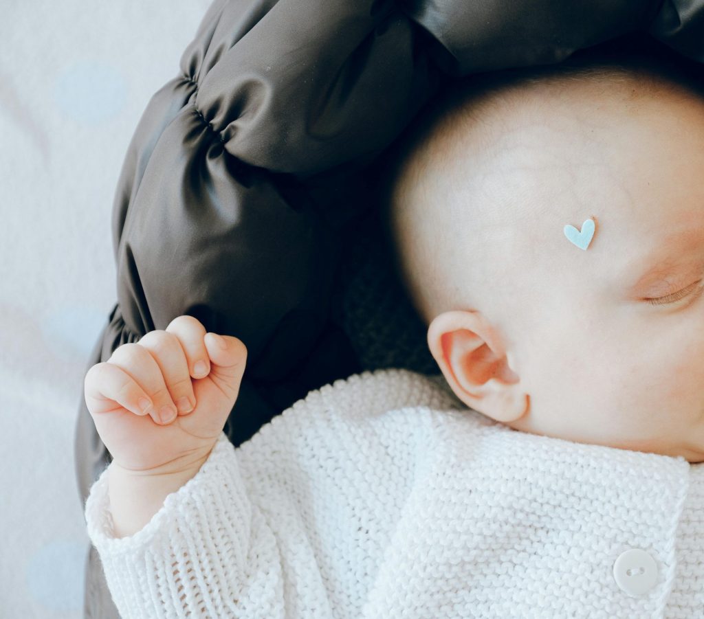 An adorable baby peacefully sleeping in a soft knitted outfit with a pacifier, exuding calmness and tenderness.