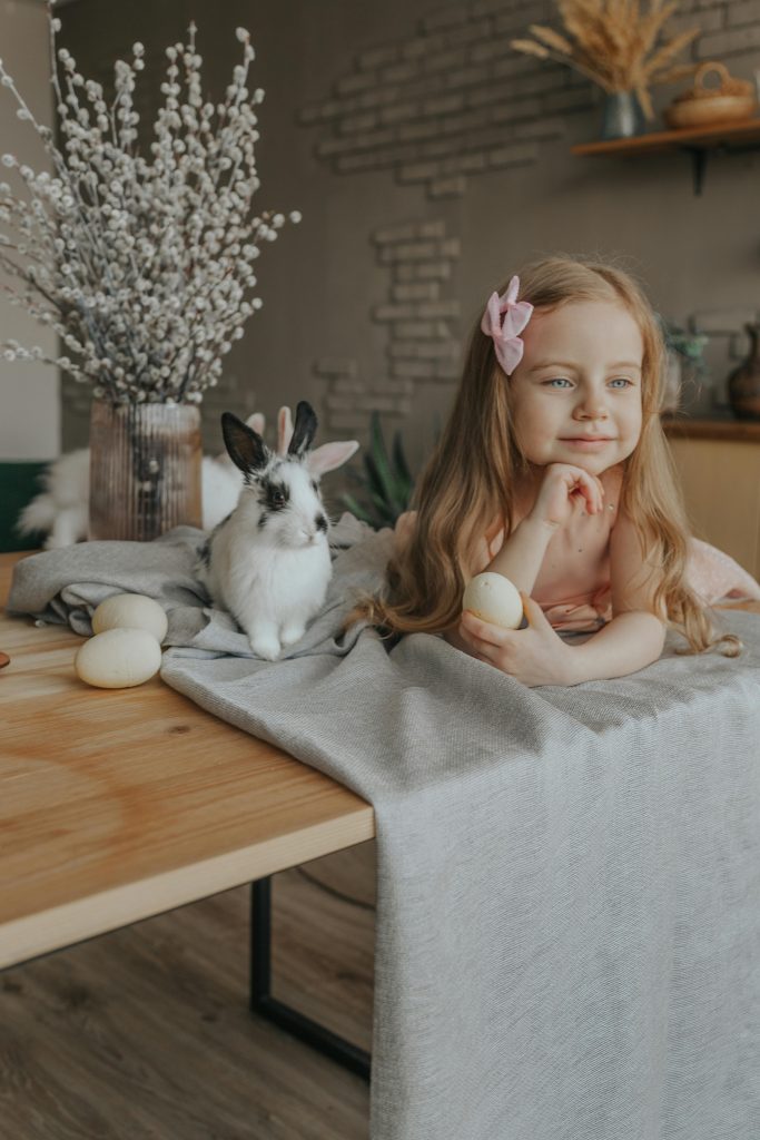 A delightful scene of a smiling girl and bunny celebrating Easter indoors.